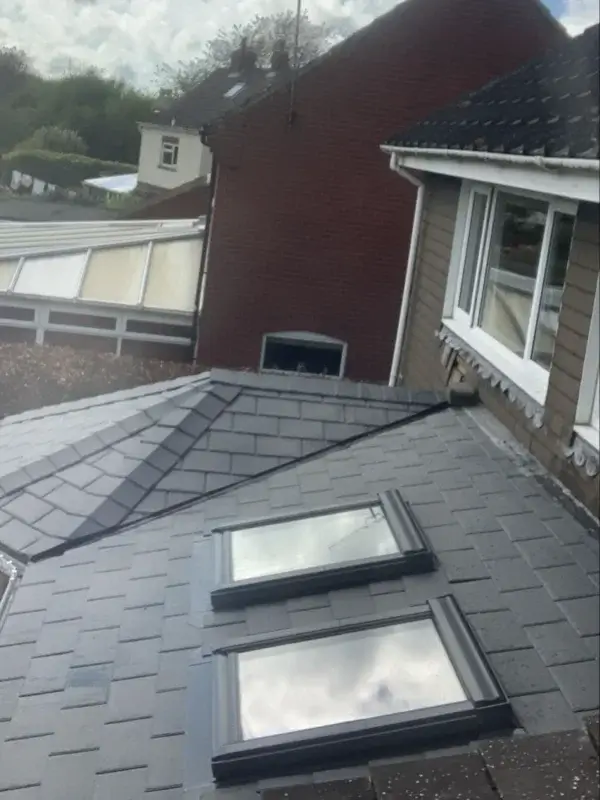 Completed grey slate-effect conservatory warm roof with two roof windows. By Norfolk Exterior Solutions.